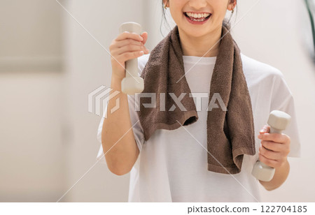 Young woman training with dumbbells 122704185