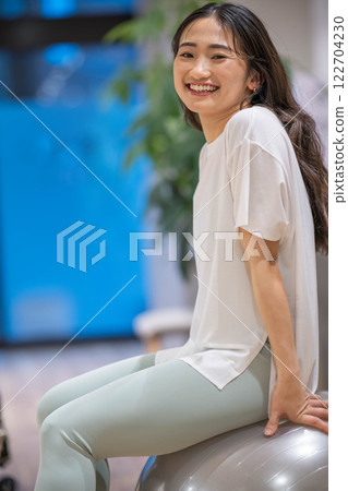 Young woman exercising with balance ball in indoor gym 122704230