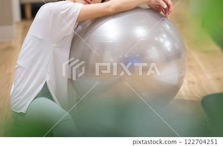 Young woman exercising with balance ball in indoor gym 122704251