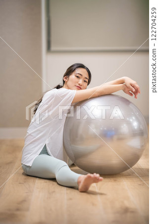 Young woman exercising with balance ball in indoor gym Young woman exercising with balance ball in indoor gym 122704259