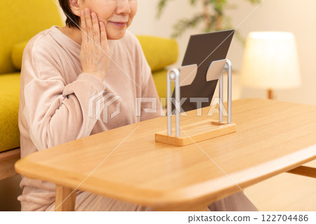 A middle-aged woman in pajamas doing skin care in a room on a winter night 122704486