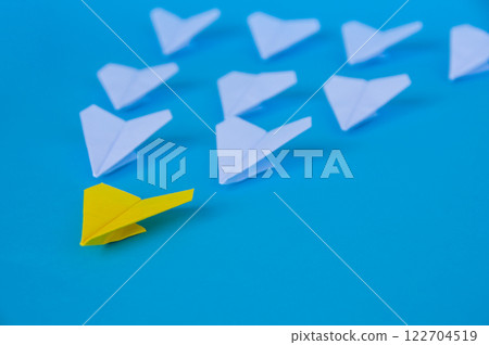 Yellow paper airplane origami leading other white airplanes on blue background with customizable space for text. Business and Leadership skills concept Yellow paper airplane origami leading other white airplanes on blue background with customizable space for text. Business and Leadership skills concept 122704519