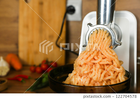 Minced chicken comes out of the metal meat grinder and sinks into a black plate on a wooden background next to vegetables, herbs and spices in out-of-focus. The concept of dietary recipes, proper and Minced chicken comes out of the metal meat grinder and sinks into a black plate on a wooden background next to vegetables, herbs and spices in out-of-focus. The concept of dietary recipes, proper and 122704578
