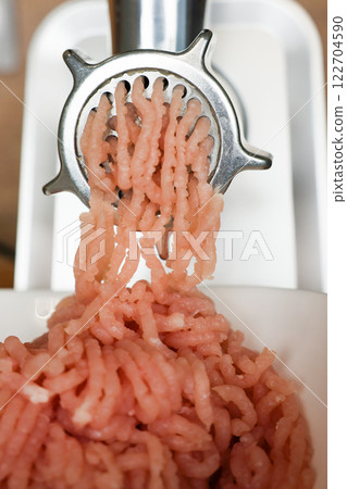 Close-up of pink minced turkey coming out of a metal meat grinder into a white plate. The concept of dietary recipes, proper and healthy nutrition, the cooking process. High quality photo Close-up of pink minced turkey coming out of a metal meat grinder into a white plate. The concept of dietary recipes, proper and healthy nutrition, the cooking process. High quality photo 122704590