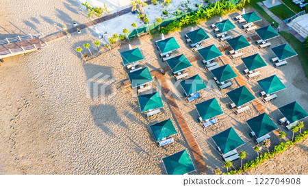 Aerial view of a scenic beach resort with rows of umbrellas and lounge chairs. Aerial view of a scenic beach resort with rows of umbrellas and lounge chairs. 122704908