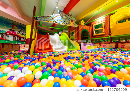 A spacious indoor playground with colorful ball pits and vibrant slides for endless fun. 122704909