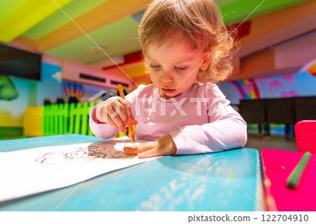 A curious child developing artistic skills in a vibrant and playful environment. 122704910