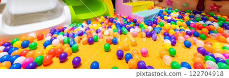 A panoramic view of a vibrant ball pit with slide exits in a playful indoor playground. 122704918