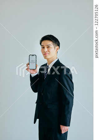 A young man in his twenties holding a smartphone 122705126