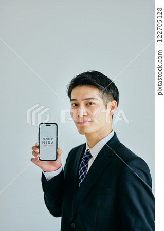 A young man in his twenties holding a smartphone 122705128