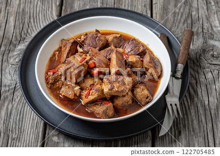 beef stew in a white bowl on rustic wooden table 122705485
