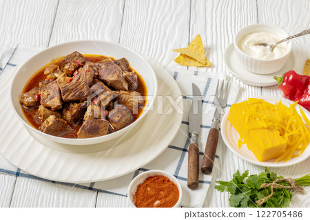 beef stew in a white bowl on rustic wooden table 122705486