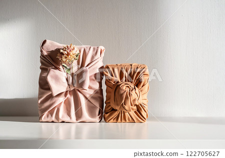 Elegant fabric wrapped gift boxes with dried flowers, styled on white table. Organic and perfect for zero waste holiday. 122705627