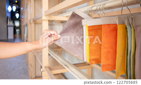 Stylist hand choosing brown fabric piece from fabric swatch material 122705685