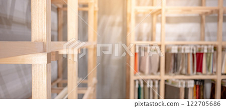Modern wooden showcase rack with blurred fabric swatch materials hanging in the background 122705686