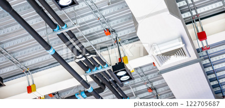 Electrical cable conduits wiring with junction boxes, part of plumbing pipeline and ceiling air vent 122705687