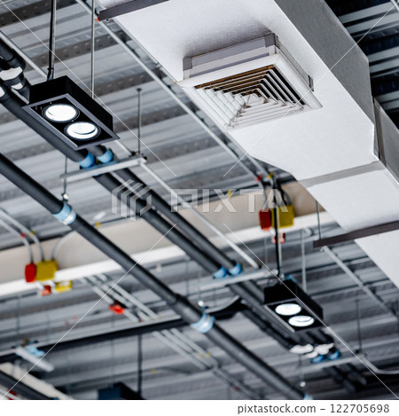 Electrical cable conduits wiring with junction boxes, part of plumbing pipeline and ceiling air vent 122705698