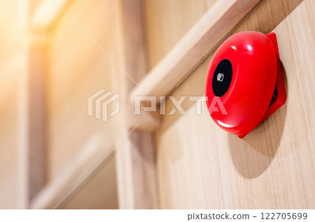 Red fire alarm bell mounted on wooden wall in office interior 122705699