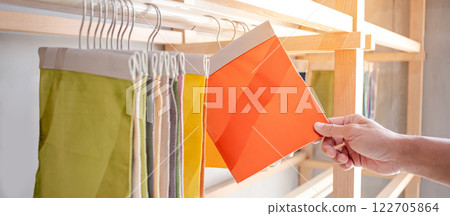 Stylist hand choosing orange fabric piece from fabric swatch material 122705864