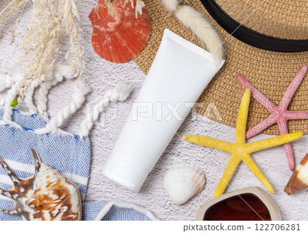 Sunscreen cream tube on hat near towel, seashells and starfishes top view, cosmetic mockup Sunscreen cream tube on hat near towel, seashells and starfishes top view, cosmetic mockup 122706281