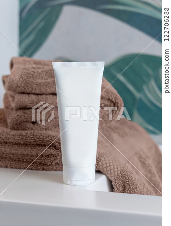 White cream tube near brown folded towels on basin in tropical bathroom close up, cosmetic mockup White cream tube near brown folded towels on basin in tropical bathroom close up, cosmetic mockup 122706288