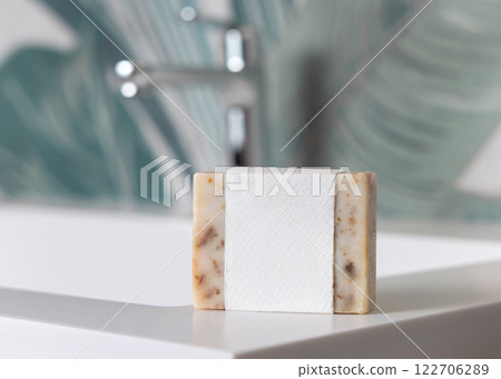 Beige soap with blank label on basin near faucet in tropical bathroom close up, mockup 122706289