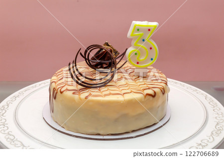 Birthday cake with a candle number three for celebrating 3 years or 3 decades of life - set on a table Birthday cake with a candle number three for celebrating 3 years or 3 decades of life - set on a table 122706689