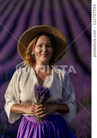 A woman wearing a straw hat and holding a bunch of lavender flowers A woman wearing a straw hat and holding a bunch of lavender flowers 122707559