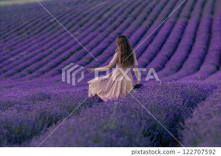 A woman is walking through a field of purple flowers 122707592