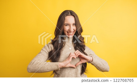 Smiling woman forming heart shape with hands 122708705