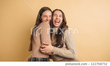 Two women laughing and embracing joyfully together 122708732