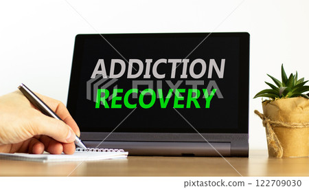 Addiction recovery symbol. Concept words Addiction recovery on beautiful tablet. Psychologist hand. Beautiful wooden table white background. Psychology addiction recovery concept. Copy space. Addiction recovery symbol. Concept words Addiction recovery on beautiful tablet. Psychologist hand. Beautiful wooden table white background. Psychology addiction recovery concept. Copy space. 122709030