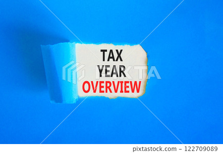 Tax year overview symbol. Concept words Tax year overview on beautiful white paper. Beautiful blue table blue background. Business tax year overview concept. Copy space. Tax year overview symbol. Concept words Tax year overview on beautiful white paper. Beautiful blue table blue background. Business tax year overview concept. Copy space. 122709089