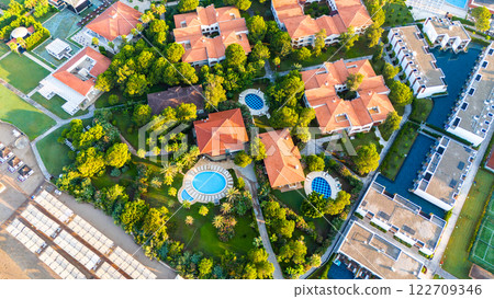 Aerial view of a luxury beachfront resort with private villas, pools, and lush greenery Aerial view of a luxury beachfront resort with private villas, pools, and lush greenery 122709346