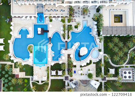 Aerial view of a luxury resort with a uniquely designed pool, lush gardens, and elegant sunbathing areas Aerial view of a luxury resort with a uniquely designed pool, lush gardens, and elegant sunbathing areas 122709418