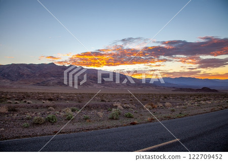 Scenic desert road at sunset with colorful clouds and mountain backdrop 122709452