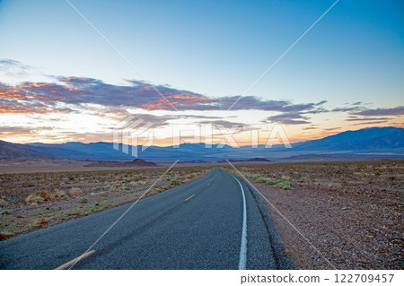 Scenic desert road at sunset with colorful clouds and mountain backdrop 122709457