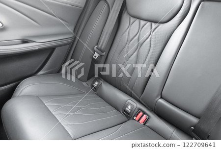Back passenger black seats in modern luxury car. Black perforated leather with white stitching. Car details. Leather comfortable seats. Car interior details 122709641