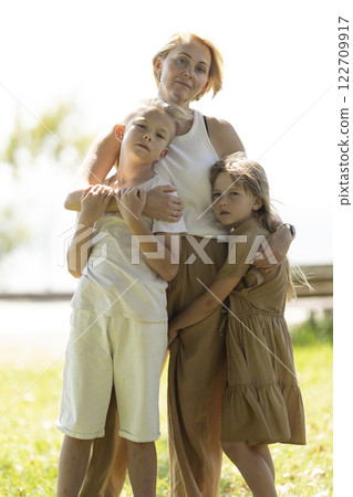 Mother embracing children in sunlit park Mother embracing children in sunlit park 122709917