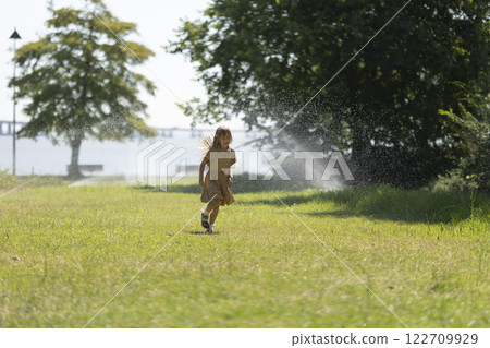 Young girl running through a sunny park 122709929