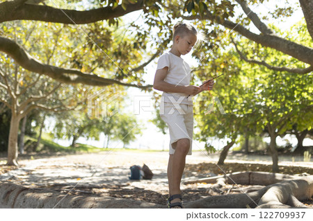 Young boy engaging with digital tablet outdoors Young boy engaging with digital tablet outdoors 122709937