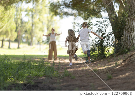 Children running towards parent in sunny forest 122709968