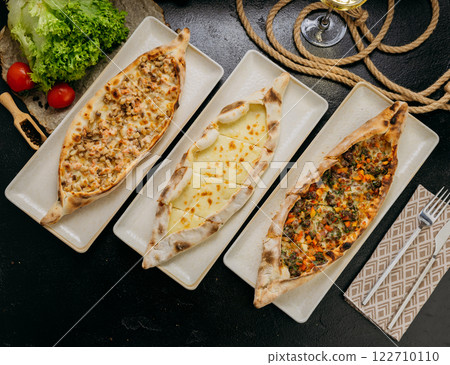 Assorted Turkish pide with cheese, minced meat and chicken served on plates in a gourmet setting Assorted Turkish pide with cheese, minced meat and chicken served on plates in a gourmet setting 122710110