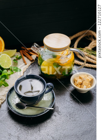 Herbal citrus tea with fresh mint, lime, orange and brown sugar served in a glass teapot and cup Herbal citrus tea with fresh mint, lime, orange and brown sugar served in a glass teapot and cup 122710127