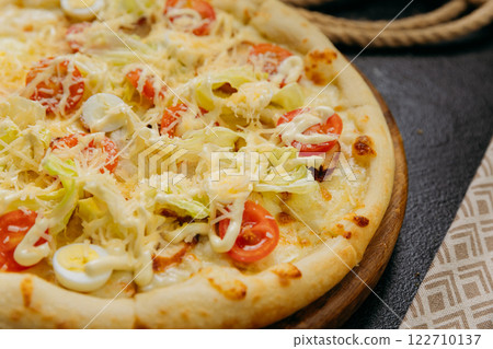 Caesar salad pizza with cherry tomatoes, quail eggs, lettuce, and parmesan, served on a wooden board Caesar salad pizza with cherry tomatoes, quail eggs, lettuce, and parmesan, served on a wooden board 122710137