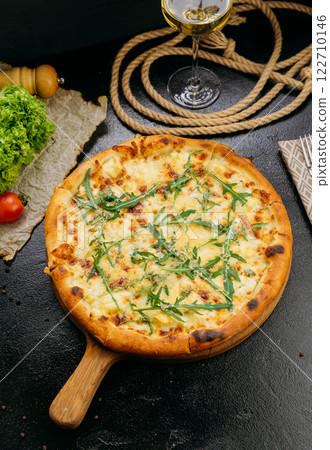 Gourmet four-cheese pizza with arugula, served on a wooden board in a stylish restaurant setting Gourmet four-cheese pizza with arugula, served on a wooden board in a stylish restaurant setting 122710146