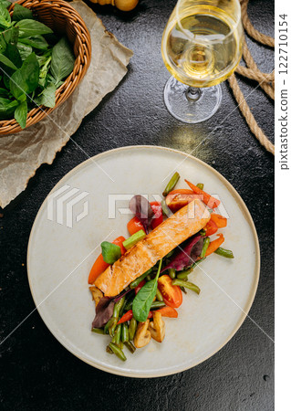 Grilled salmon fillet with fresh vegetables, served on a plate, elegant food presentation 122710154