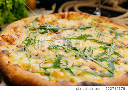 Gourmet four-cheese pizza with arugula, served on a wooden board in a stylish restaurant setting Gourmet four-cheese pizza with arugula, served on a wooden board in a stylish restaurant setting 122710176