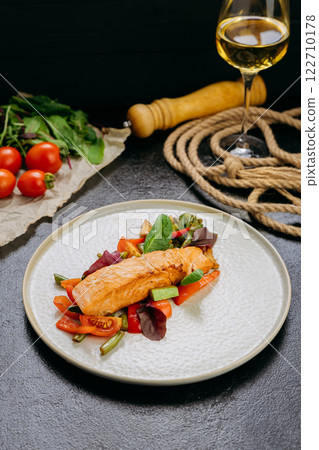 Grilled salmon fillet with fresh vegetables, served on a plate, elegant food presentation 122710178