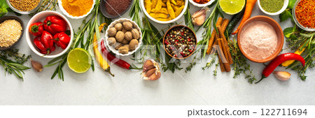 A vibrant assortment of spices and herbs on a gray background, offering a flavorful addition to any recipe, top view and copy space, banner 122711694